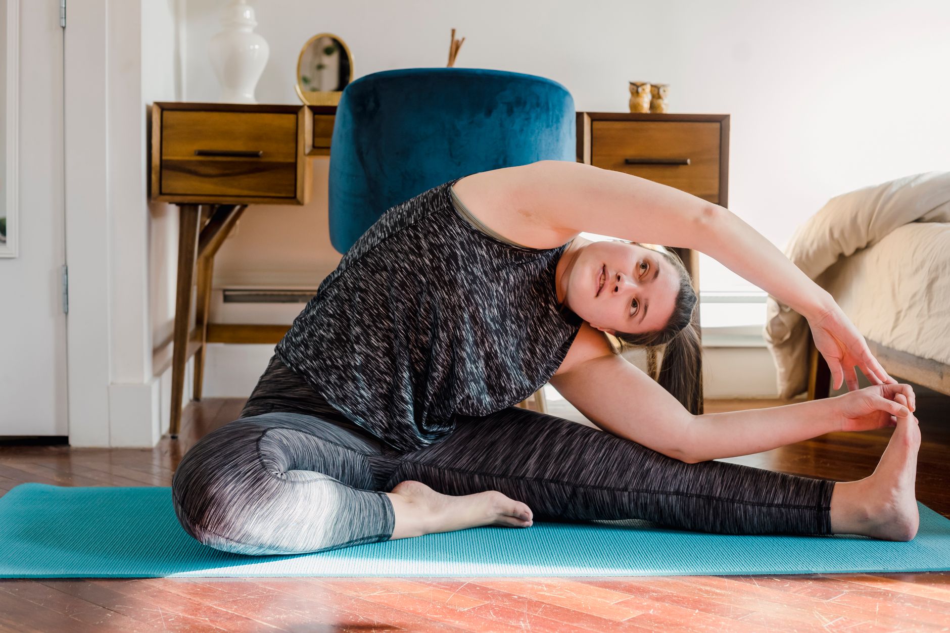 Woman stretching on a mat in a sunny living room before work