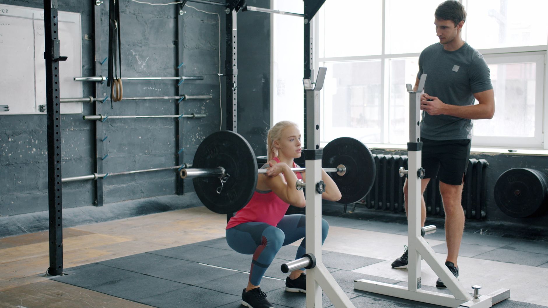 Woman lifting a barbell in a bright gym